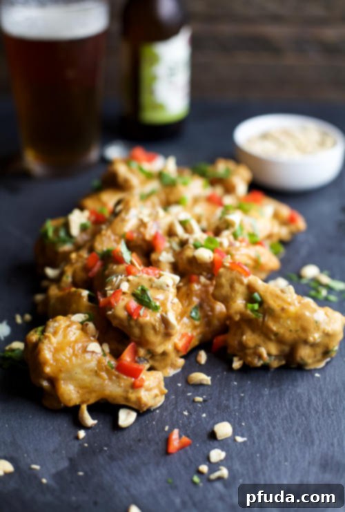 Crispy Baked Chicken Wings tossed in a spicy Thai peanut sauce, a perfect dinner or game day snack.