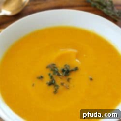 Butternut Squash soup in a white bowl with thyme on top and in the background.