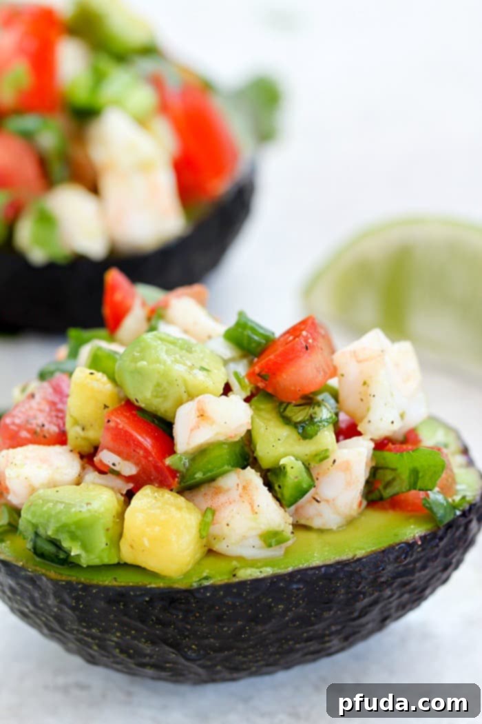The Best Easy Avocado Shrimp Ceviche Recipe with a little spice! Three avocado halves filled with colorful ceviche.