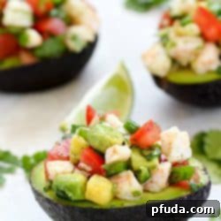 Three Avocados filled with Shrimp Ceviche on a counter with a lime garnish.