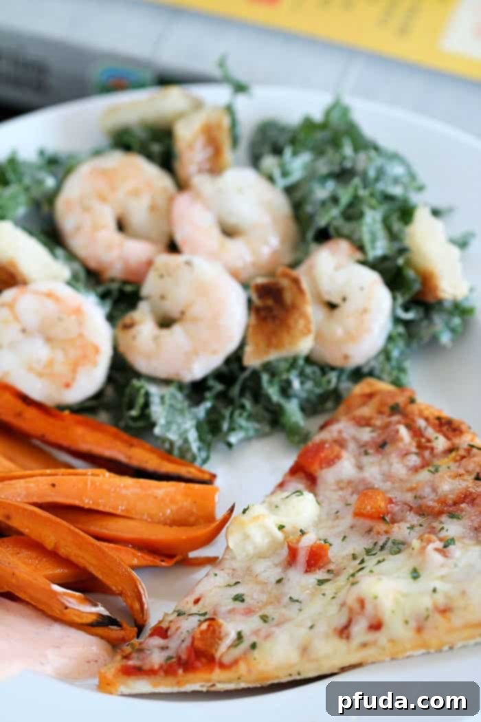 A delectable spread featuring California Pizza Kitchen frozen pizza alongside homemade Kale Caesar Salad with Shrimp and Baked Sweet Potato Fries, illustrating a balanced, easy meal.