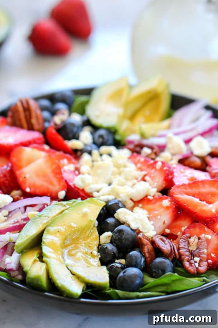 An irresistible spinach salad featuring California avocado, mixed berries, feta cheese, and walnuts, drenched in a homemade honey-garlic dressing – a truly flavorful and easy meal.