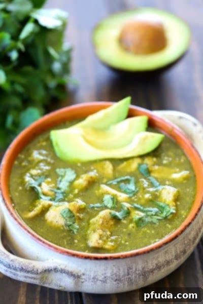 A bowl of delicious Pork Chili Verde, garnished with fresh cilantro and lime wedges.