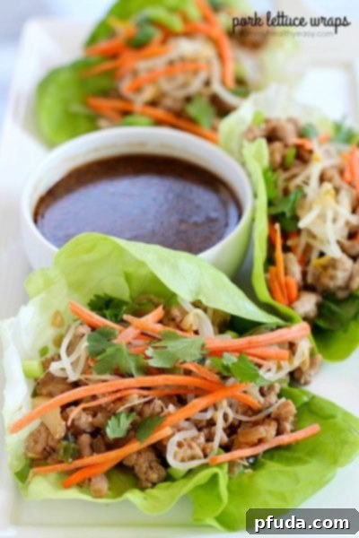 Hand holding a crisp lettuce cup filled with savory pork mixture and toppings.