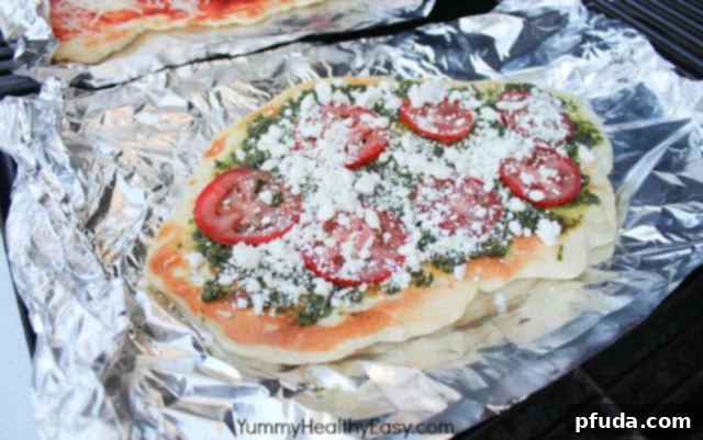 Closeup of homemade pizza dough being pressed or rolled on foil, ready for grilling.