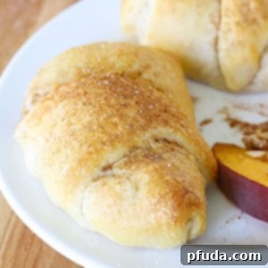 Close up of a Peach Crisp Rollup on a white plate with a side of sliced peaches.