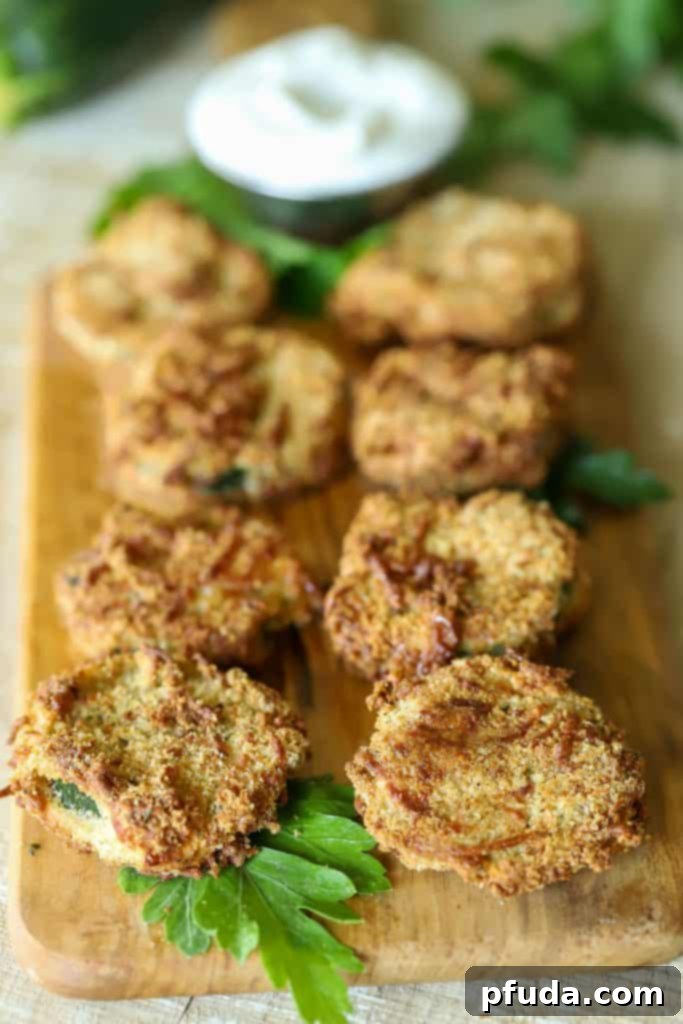 Platter of yummy breaded zucchini chips with a dipping sauce on the side.