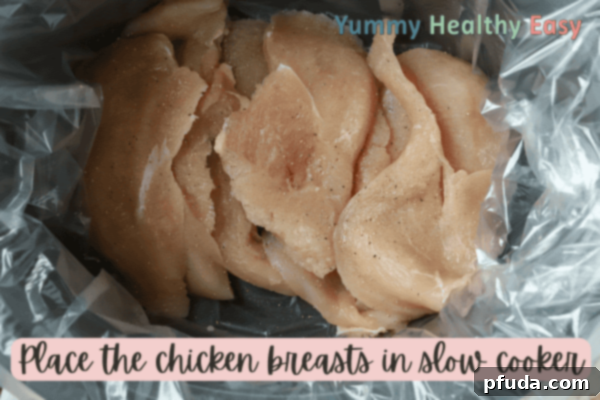 Easy Slow Cooker Low-Sodium Shredded Taco Chicken 4 Crock Pot filled with boneless skinless chicken breasts.