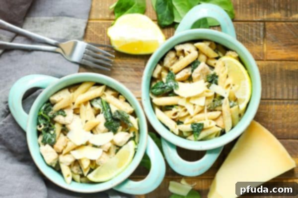 Zesty Lemon Chicken Pasta 5 sideways view of two blue bowls filled with Lemon Chicken Pasta on a wooden table.