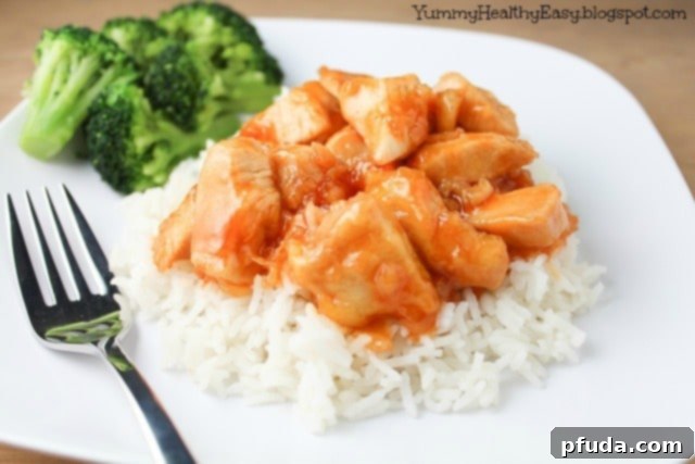 A bowl of delicious Mandarin Chicken served with rice and garnished with green onions and sesame seeds, ready for dinner