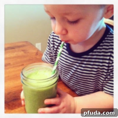 Young boy, Tate, happily drinking a green smoothie