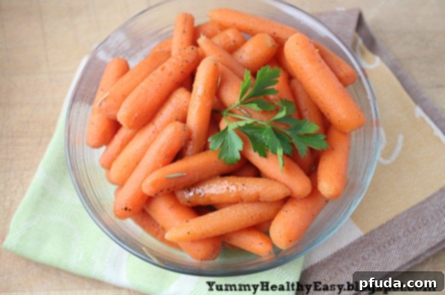 A large bowl of cooked, glistening carrots, garnished with a sprig of fresh parsley, ready for serving.