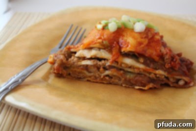 Cheesy Enchilada Stack garnished with fresh green onions, sitting on a wooden board ready for serving