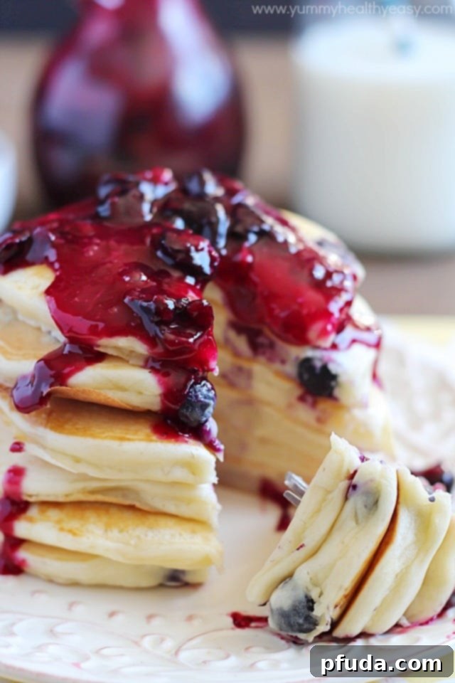 Overhead view of a beautiful plate of blueberry pancakes, showered with fresh blueberries and glistening with syrup