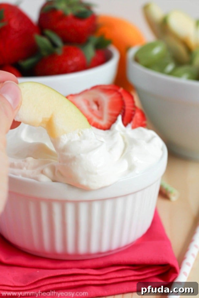 Bowl of creamy citrus fruit dip surrounded by colorful fresh fruit