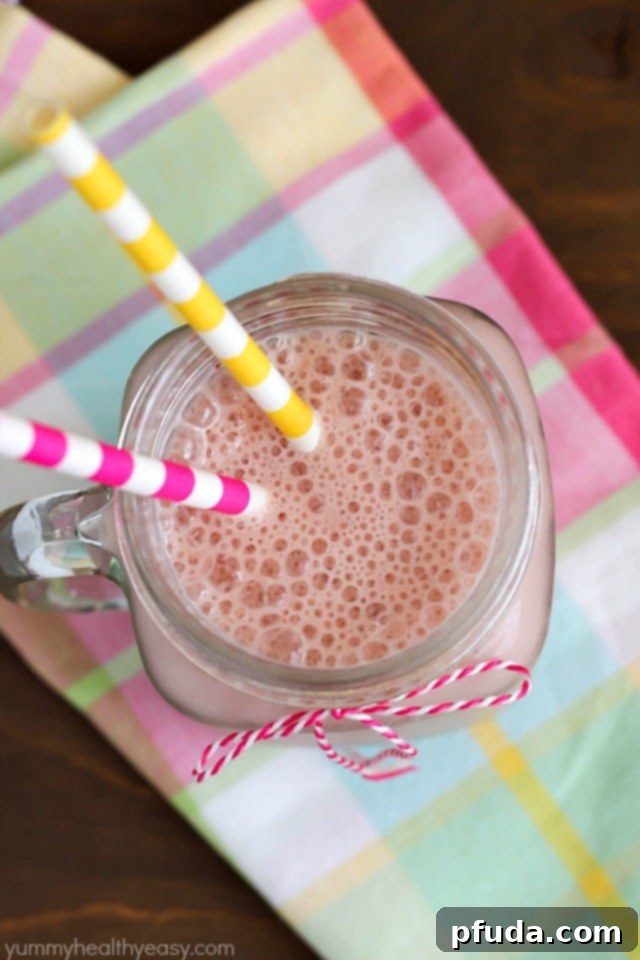 A refreshing Good Morning Smoothie glass, showcasing the vibrant colors of pomegranate, strawberry, orange, and banana, made with California dairy.