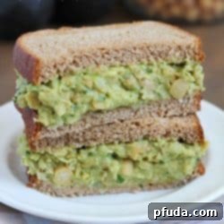 Avocado Chickpea Salad Sandwiches stacked on top of each other on a white plate.