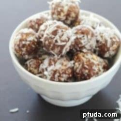 No-Bake Nut and Date Energy Balls 2 A white bowl full of No-Bake Nut & Date Energy Balls coated in shredded coconut.