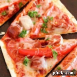 A close-up of the delicious Copycat Olive Garden Pepperoni & Sausage Flatbread Pizza, featuring melted cheese and a crispy crust.